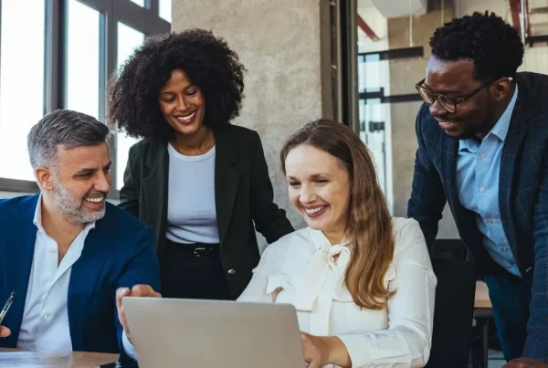 Three business professionals collaborating around a laptop during a meeting