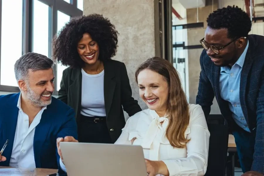Three business professionals collaborating around a laptop during a meeting